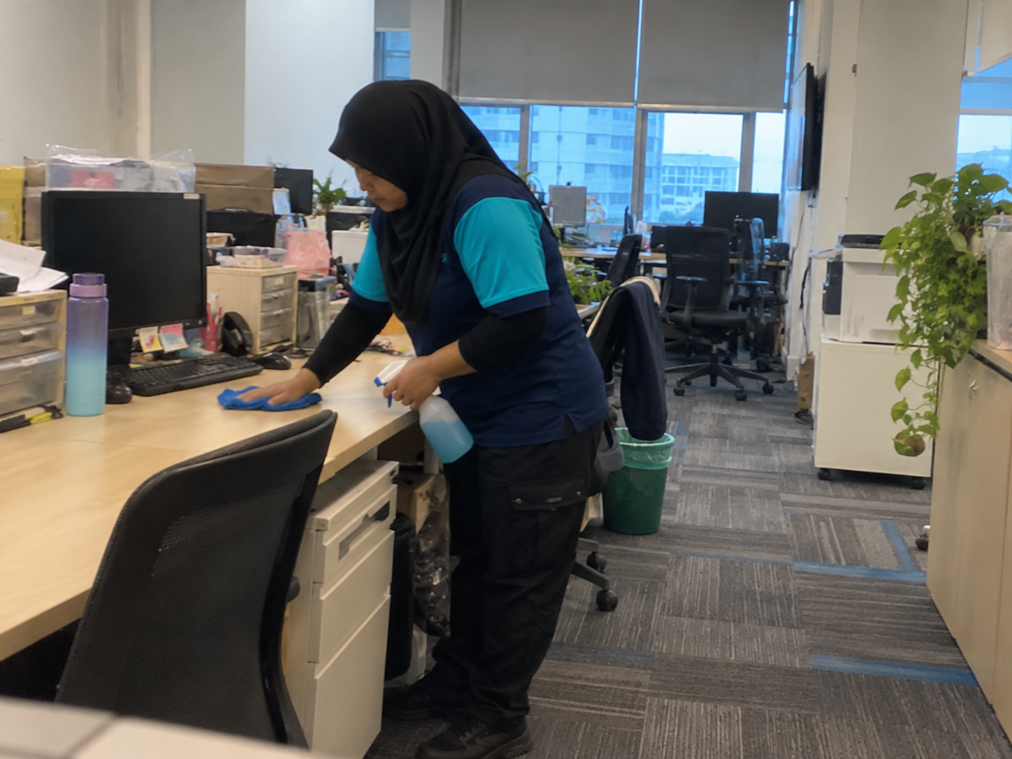 Professional cleaner wiping office workstations as part of commercial and industrial cleaning services in KL