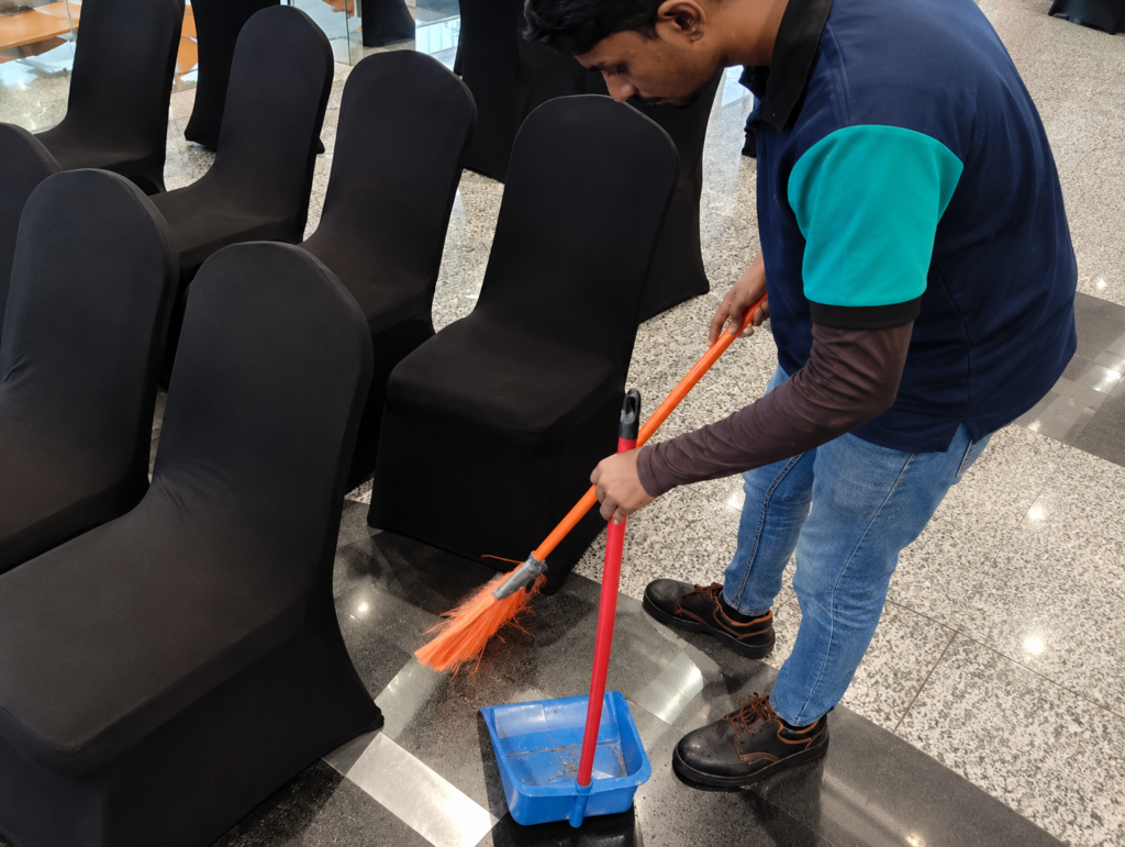 Cleaner sweeping between banquet chairs at a corporate event in Kuala Lumpur